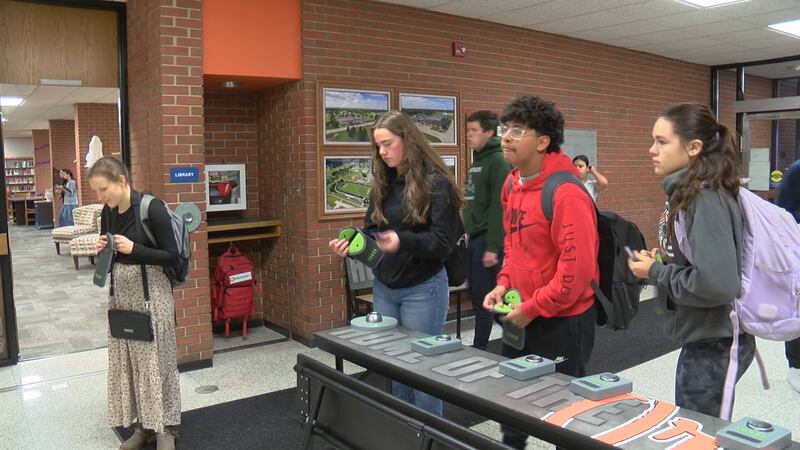 Students putting their cell phones into special pouches meant to keep them from getting...