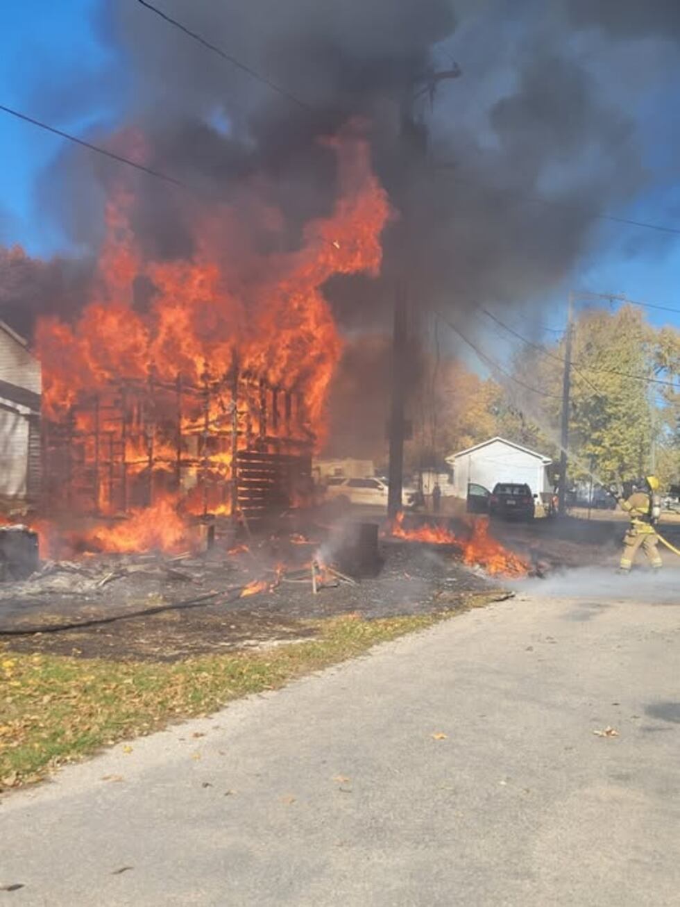 A photo shows a structure fire catching on power lines above the building and sprawling out on...